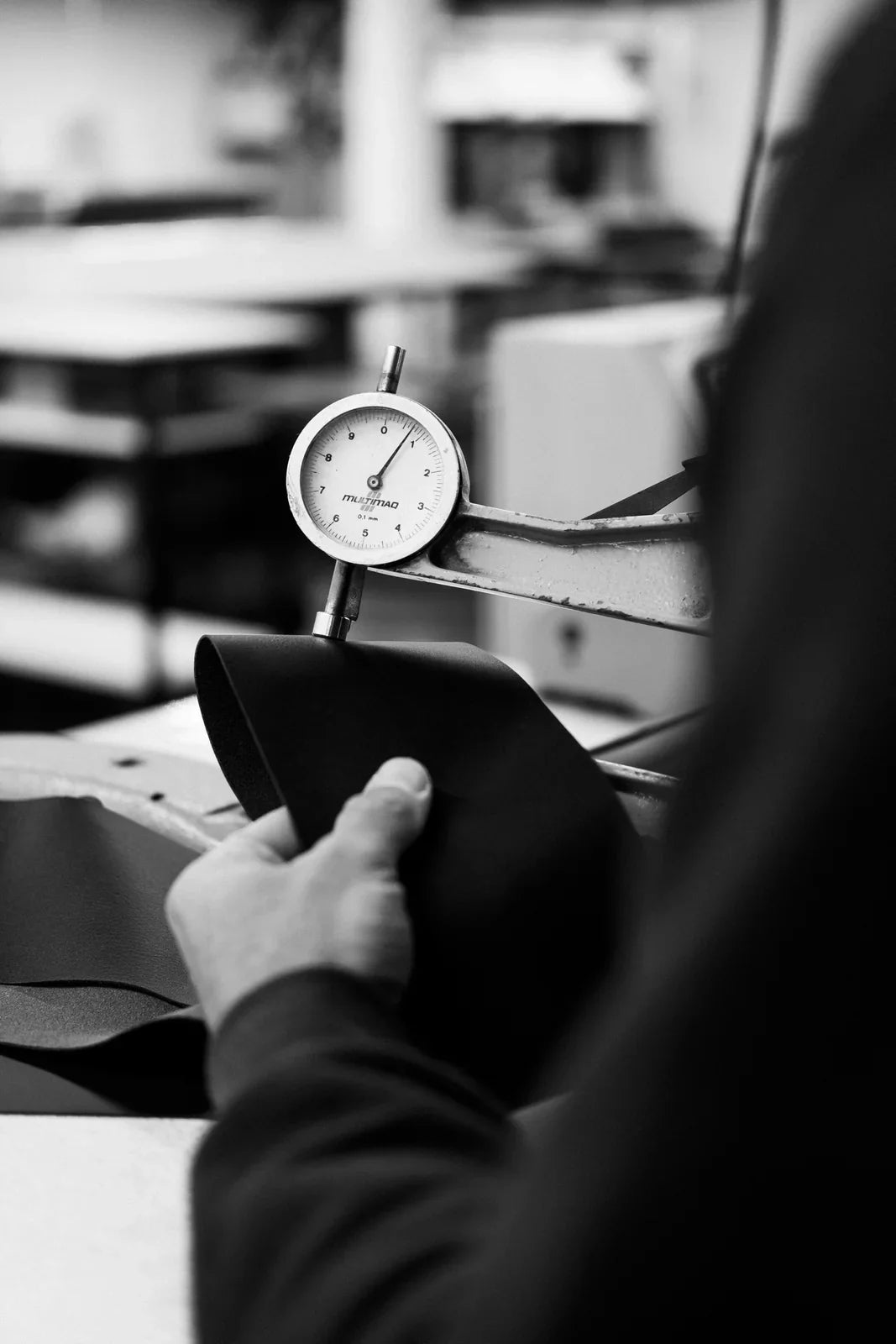 Hands holding a pressure gauge at a Nordweg workshop station, photographed in black and white.