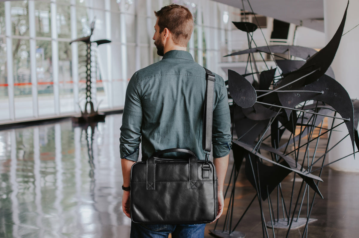 Nordweg Nomad black leather briefcase carried over the shoulder in a modern interior