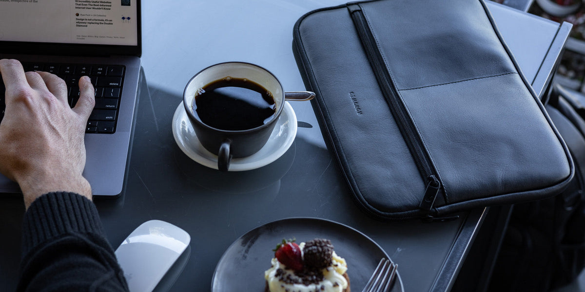 Black Nordweg Workplace leather laptop sleeve on a cafe desk with a laptop and coffee