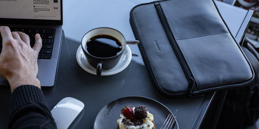 Black Nordweg Workplace leather laptop sleeve on a cafe desk with a laptop and coffee