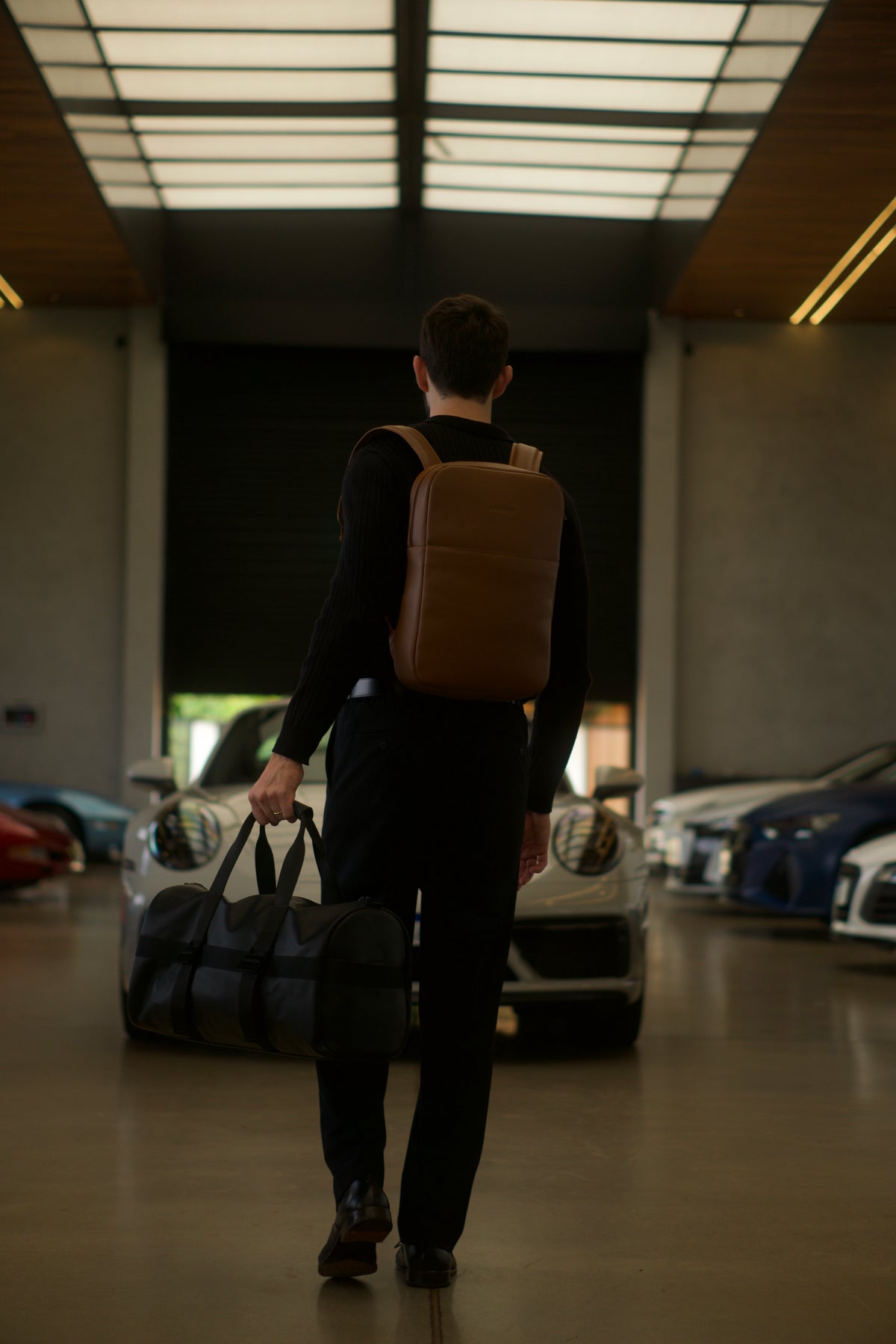 Traveler seated beside a cognac Nordweg Legacy leather backpack