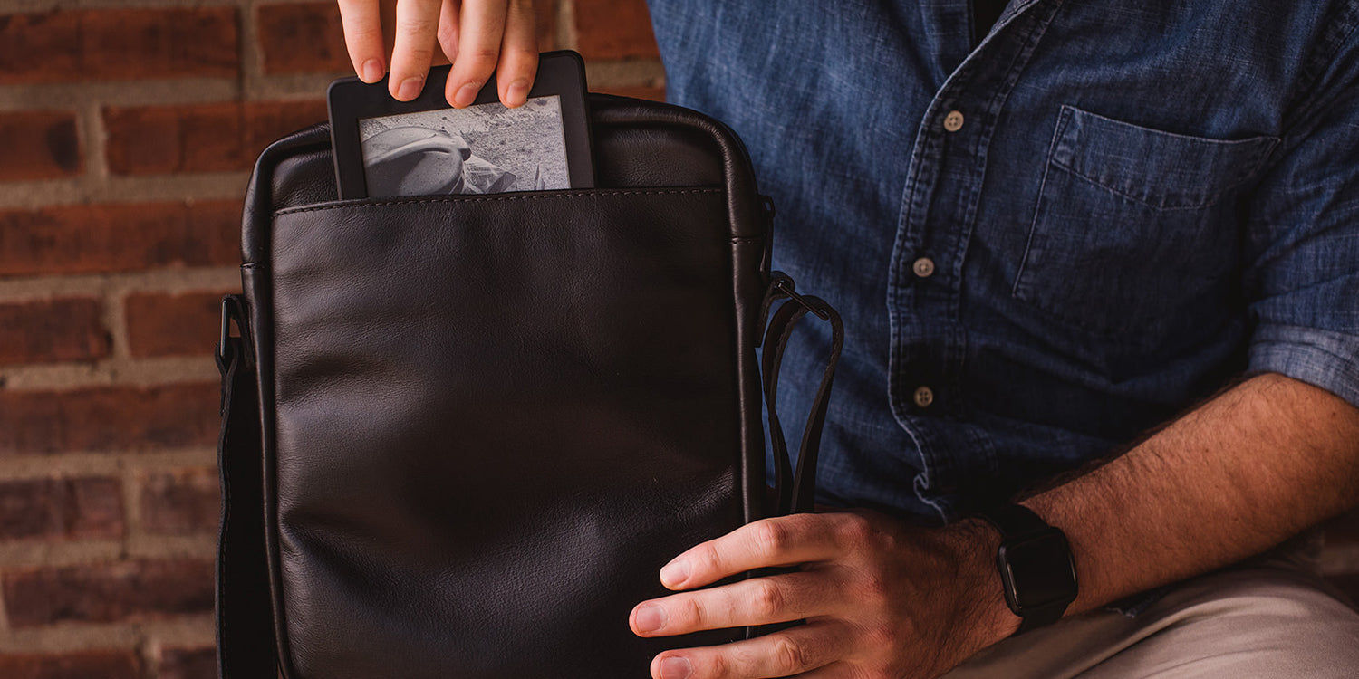 Nordweg black leather bag hand-carried in front of a brick wall, lifestyle detail photo
