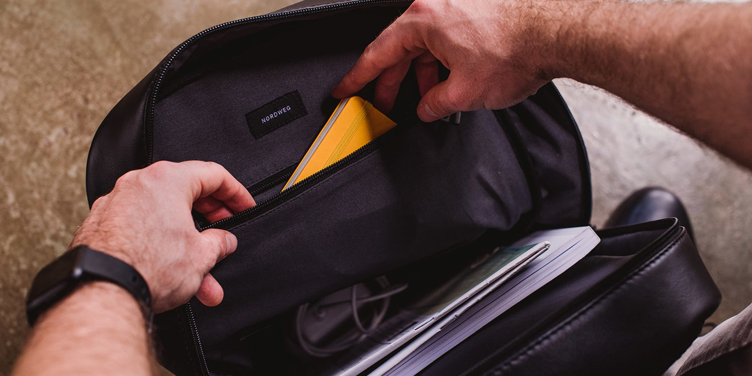 Nordweg black leather bag zipper being opened by hand in a close product detail