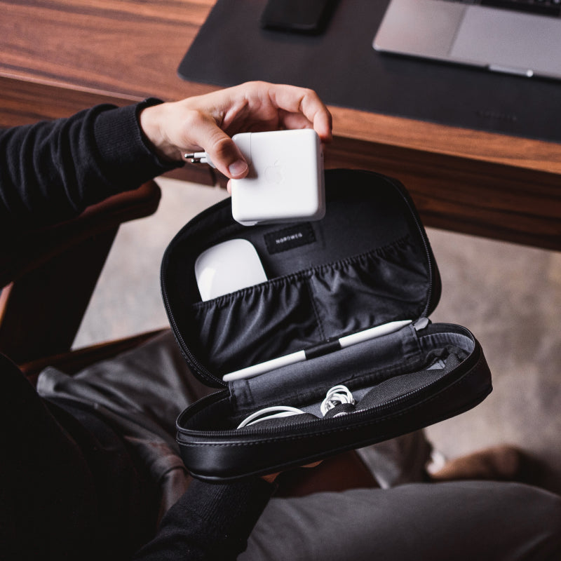Nordweg black leather dopp kit being opened by hand in a travel detail photo