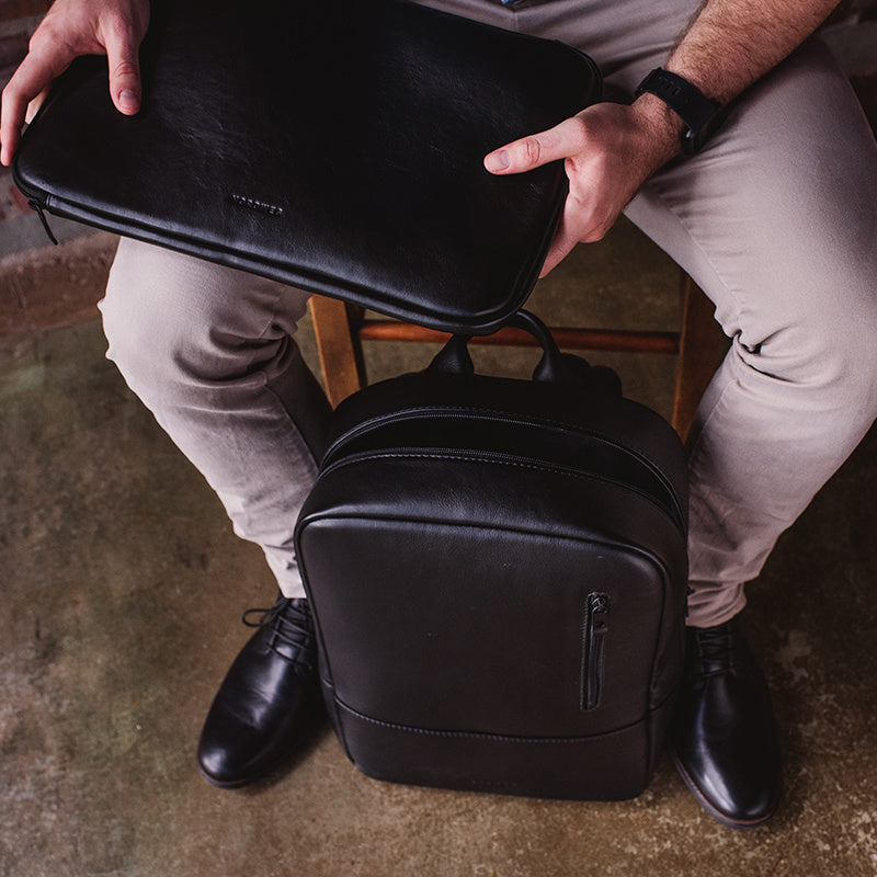 Nordweg black leather dopp kit opened by hand while seated, compact travel organizer lifestyle photo
