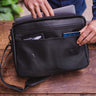 Nordweg black leather messenger briefcase open with laptop, passport, and front pocket detail
