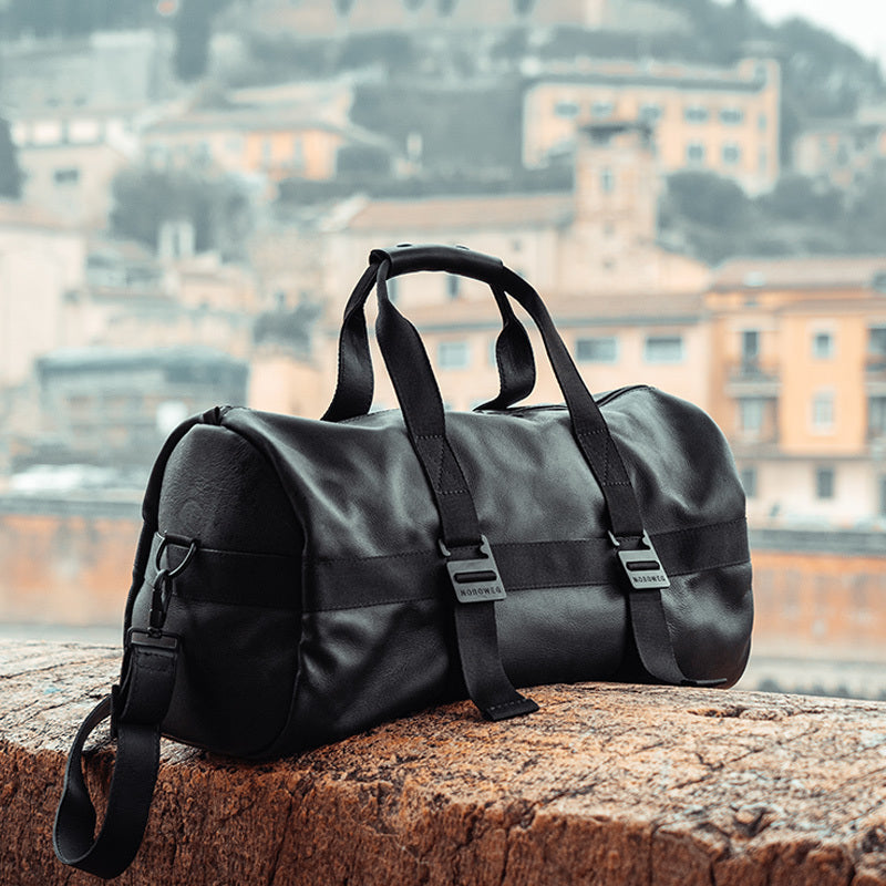 Nordweg black leather weekender duffel bag near a city waterfront, duplicate lifestyle upload