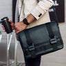 Black Nordweg Dolomites leather satchel carried over the shoulder in an airport terminal, SKU NW105.IP, GTIN 7898571001112