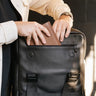 Nordweg Dolomites leather travel backpack in Black with front zip pocket holding a caramel leather accessory
