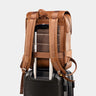 Caramel Dolomites leather travel backpack secured on a rolling suitcase handle