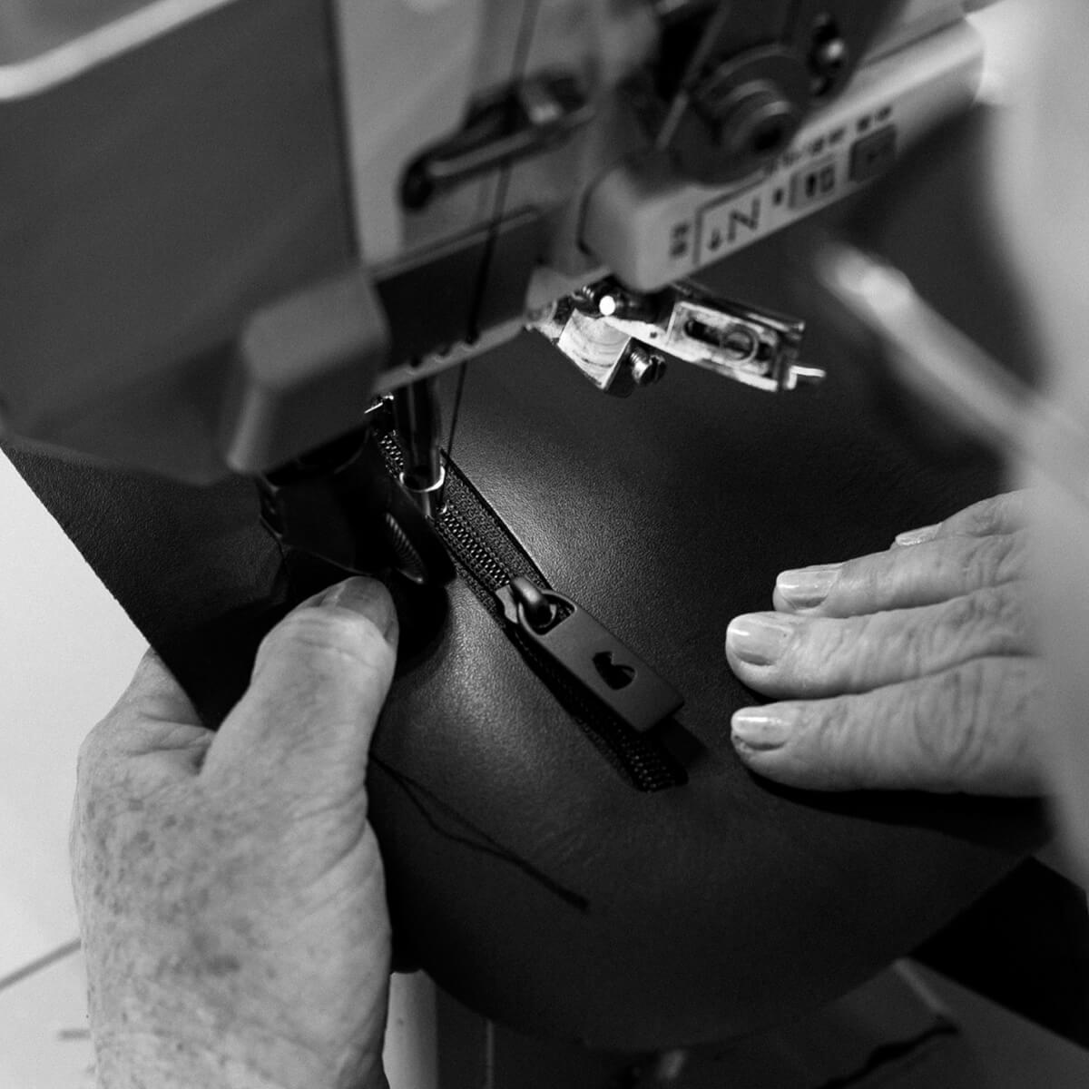 Nordweg leather workshop close-up of a sewing machine stitching a zipper into black leather