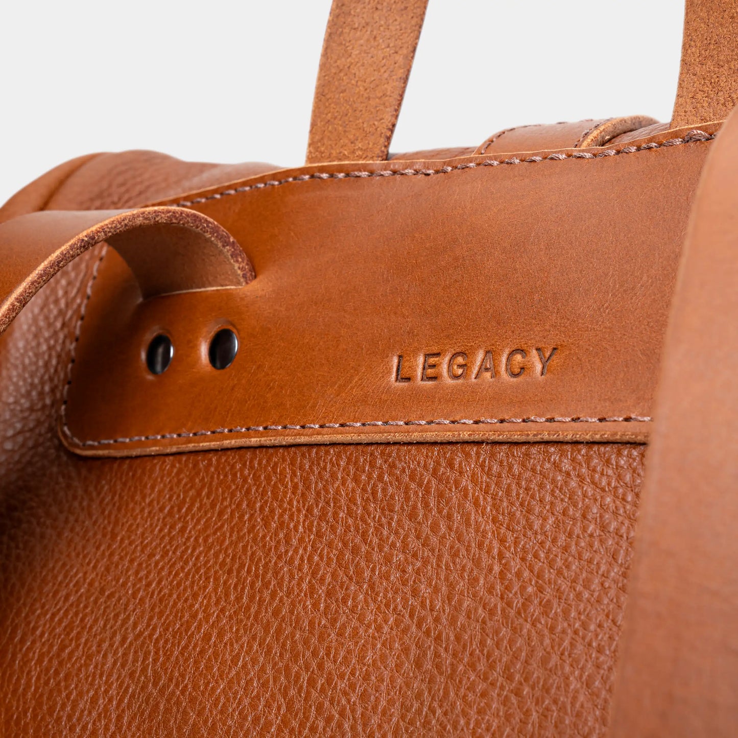 Close-up of the Legacy mark detail on the cognac Nordweg leather backpack