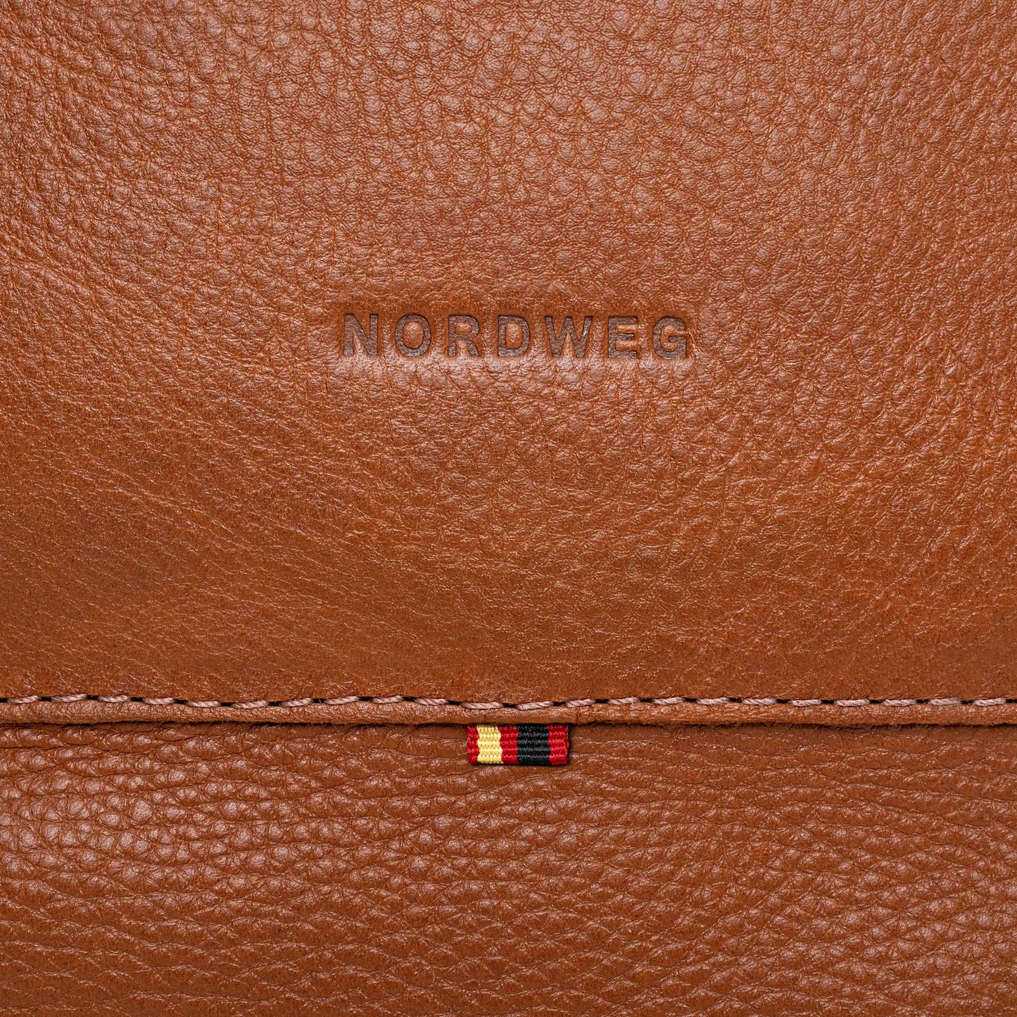 Close-up of Nordweg logo on cognac pebbled leather backpack