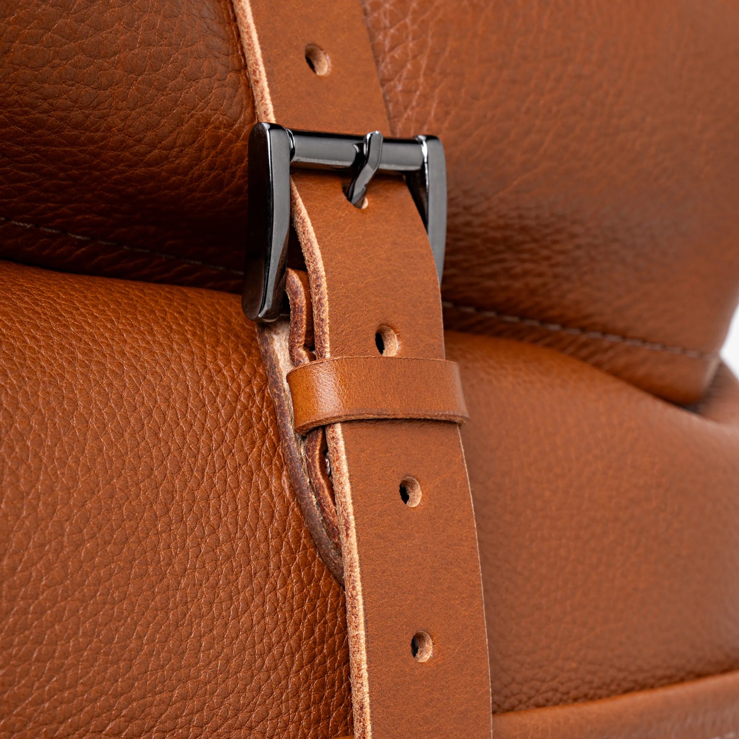 Close-up of cognac Legacy leather backpack roll-top buckle and strap detail