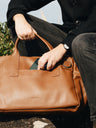 Cognac Nordweg Legacy leather briefcase with a phone being placed in an open pocket, SKU NWL003.CG, GTIN 7898571002331
