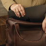 Hand inserting a tablet into the main compartment of the Nordweg Legacy Leather Briefcase in espresso