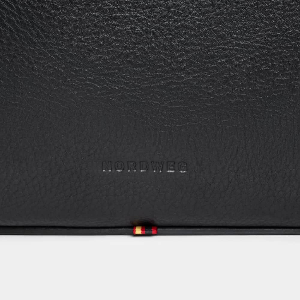 Close-up of Nordweg logo on coal pebbled leather briefcase