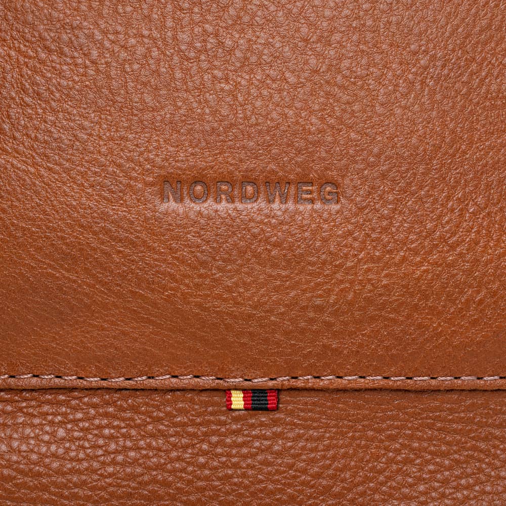 Close-up of Nordweg logo on cognac pebbled leather briefcase