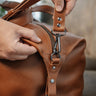 Close-up of the metal zipper pull and hook hardware on the Nordweg Legacy Leather Duffel Bag in cognac