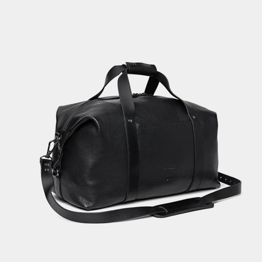 Nordweg Legacy leather duffel travel bag in coal, angled front view with shoulder strap