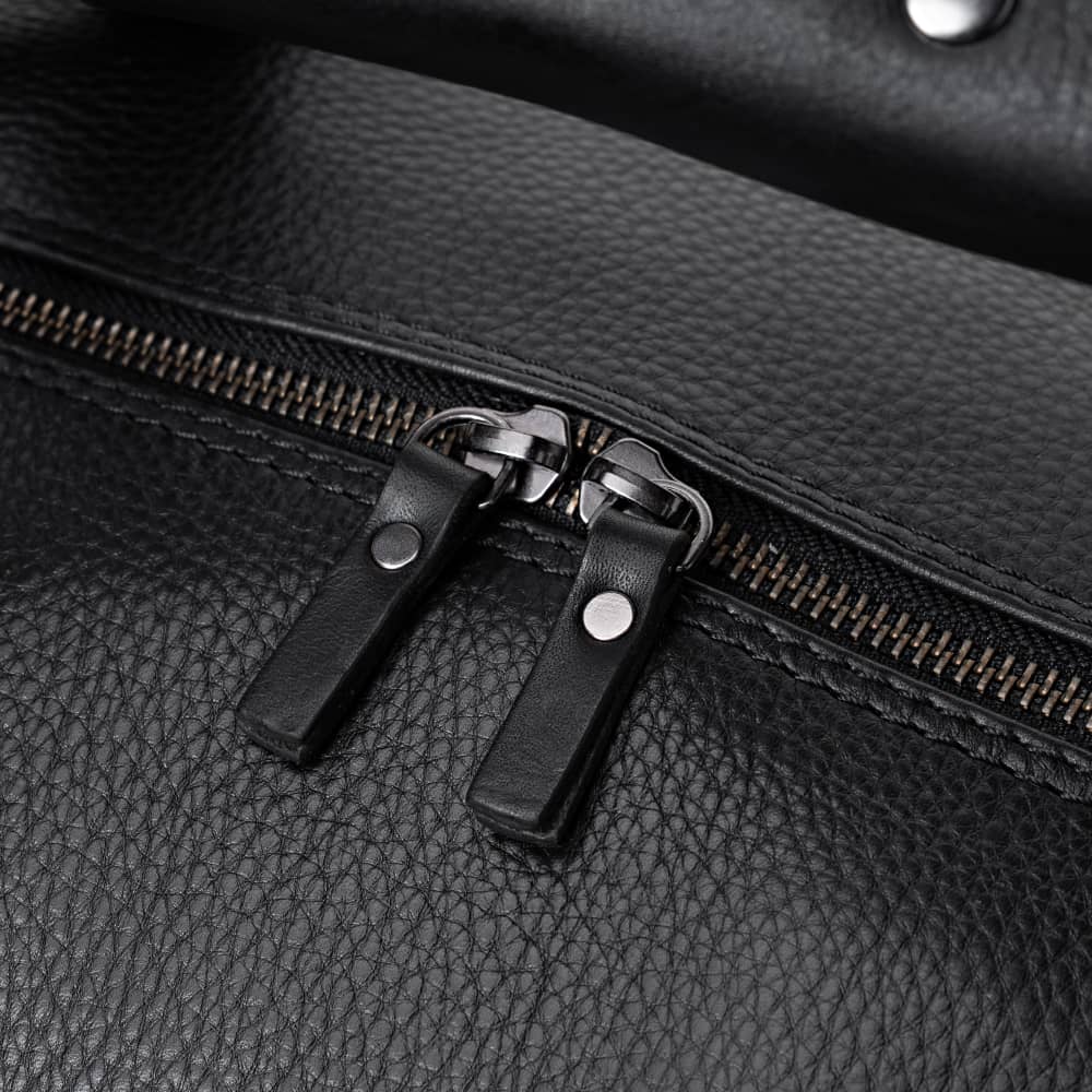 Close-up of coal Legacy leather duffel bag top zipper pulls