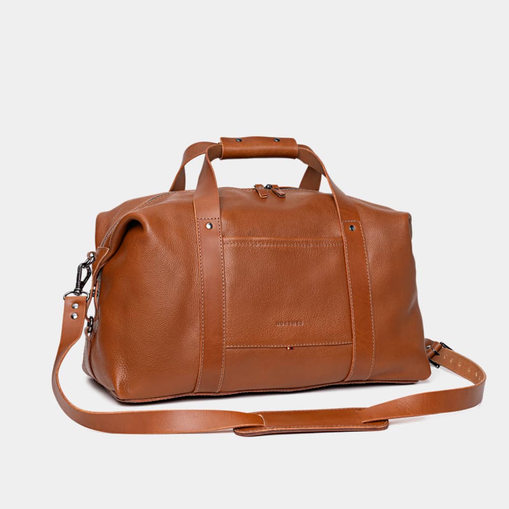Nordweg Legacy leather duffel travel bag in cognac, angled front view with shoulder strap