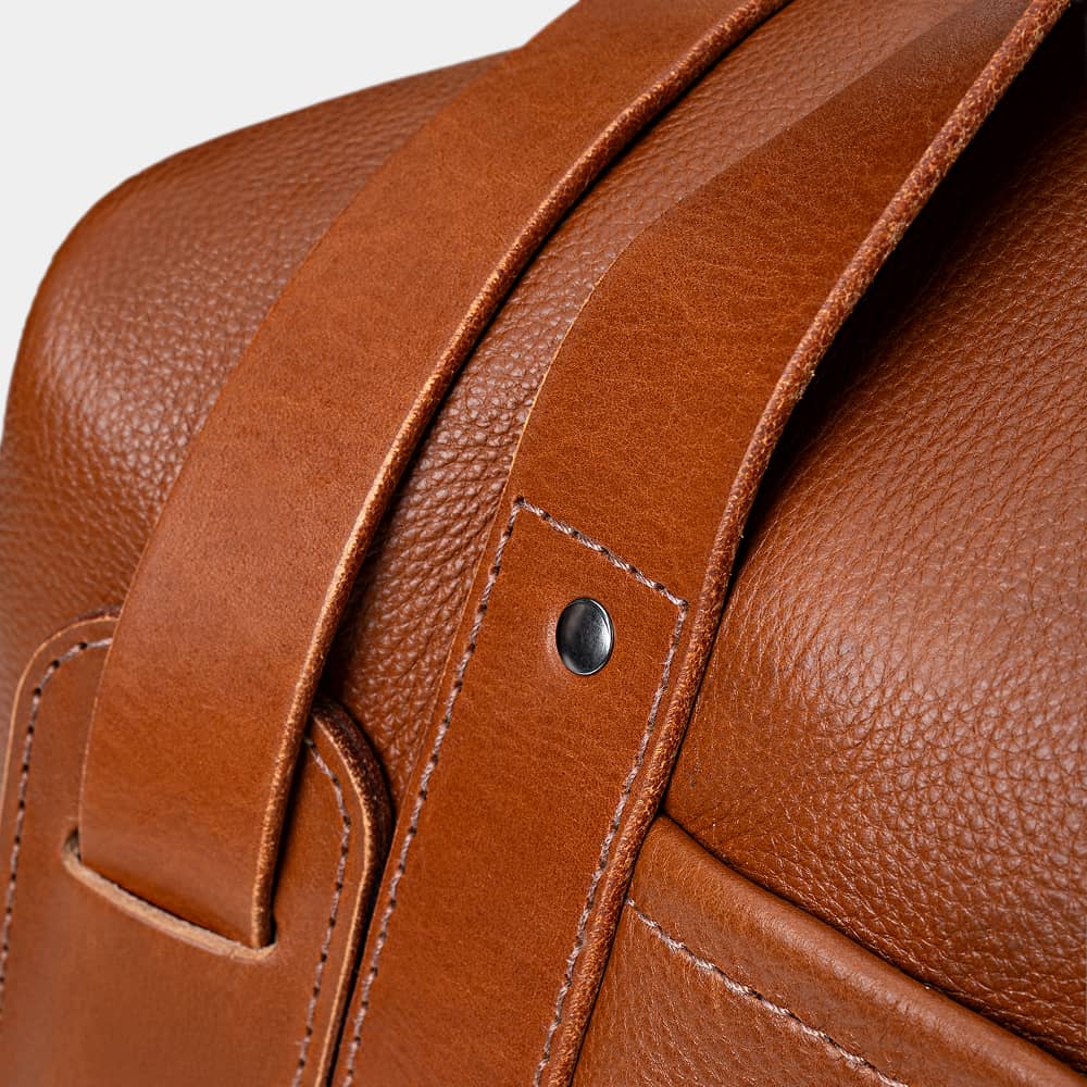 Close-up of cognac Legacy leather duffel bag handle attachment detail