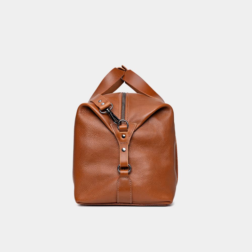 Nordweg Legacy leather duffel travel bag in cognac, side end view with handle and strap