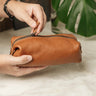 Hands opening the zipper of the Nordweg Legacy Organizer in cognac leather on a marble surface