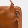 Close-up of the handle attachment and shoulder strap clip on the Nordweg Nomad Briefcase in Caramel.