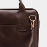 Close-up of the handle attachment and shoulder strap clip on the Nordweg Nomad Briefcase in Coffee.