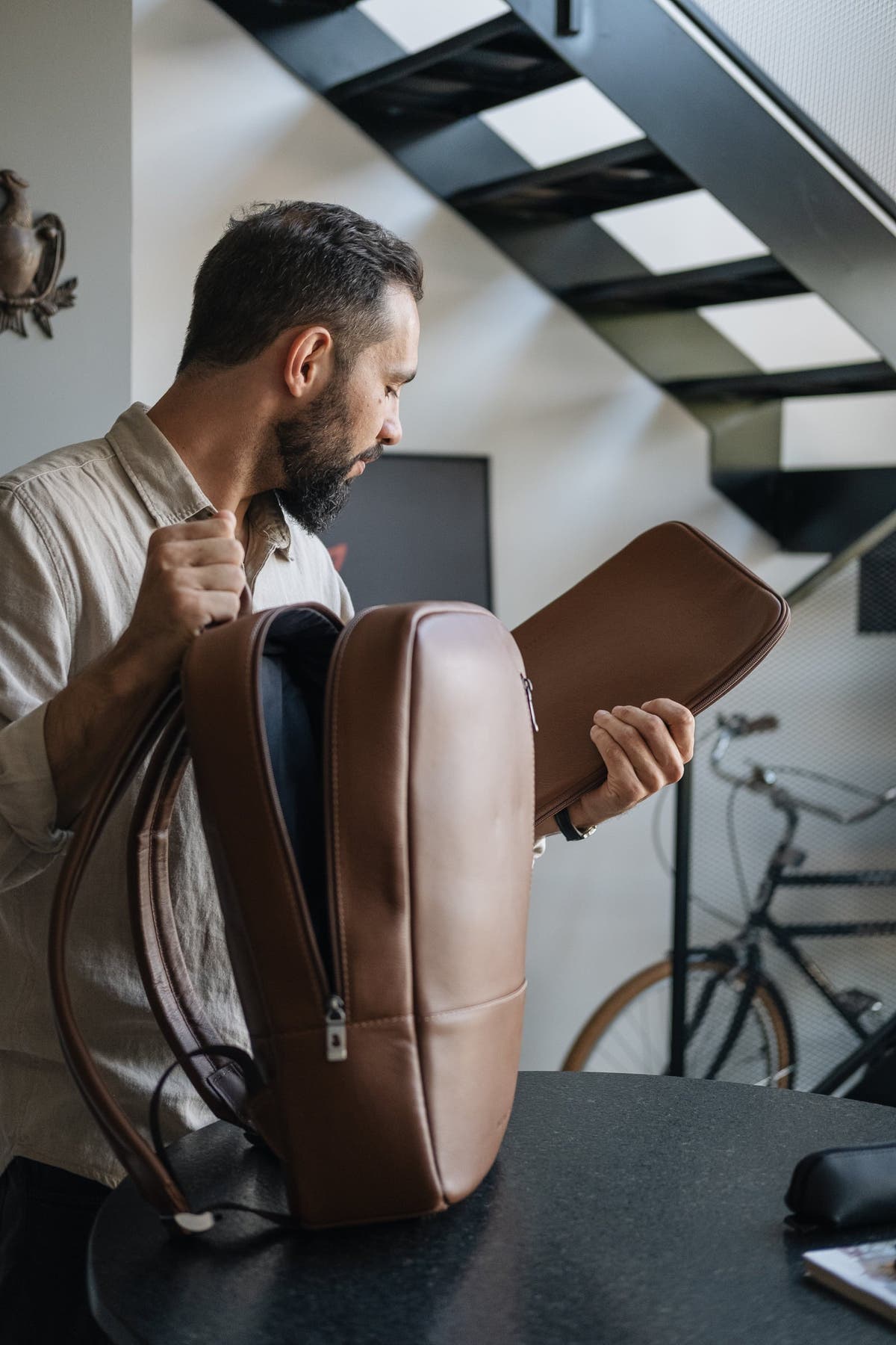 Man removing a matching leather laptop sleeve from the caramel Nordweg Nomad leather laptop backpack