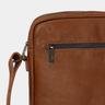 Close-up of the front zipper pull and side strap on the Nordweg Nomad Crossbody Bag in Caramel.