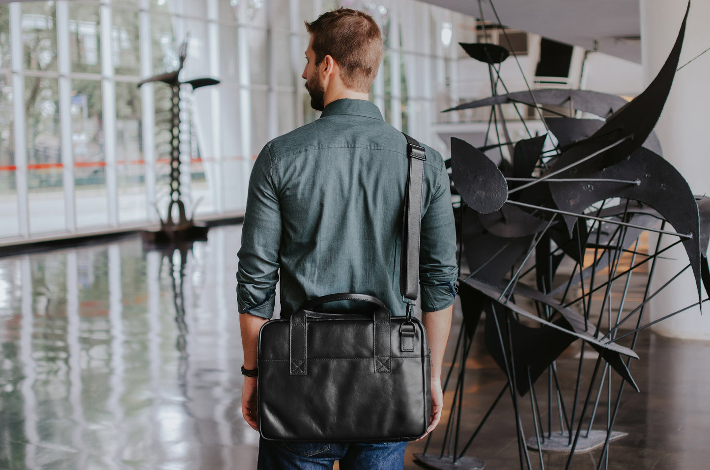 Nordweg Nomad black leather briefcase carried over the shoulder in a modern interior, SKU NW080A.IP, GTIN 7898571000696