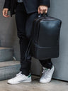Black Nordweg Nomad leather laptop backpack carried by its top handle on city steps
