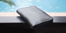 Closed Black Nomad leather passport wallet beside blue water