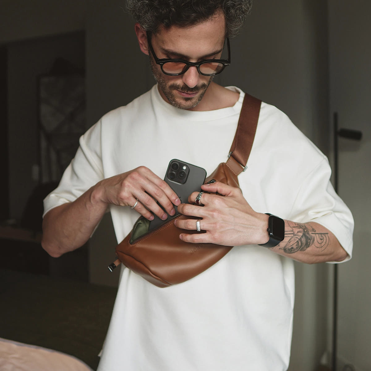 Caramel Nordweg Pulse leather sling bag worn crossbody while an iPhone is inserted, SKU NW112.CA, GTIN 7898571002232