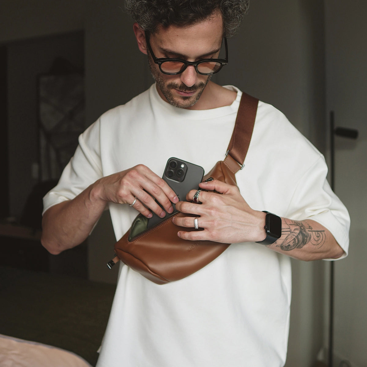 Caramel Nordweg Pulse leather sling bag worn crossbody while an iPhone is inserted, SKU NW112.CA, GTIN 7898571002232