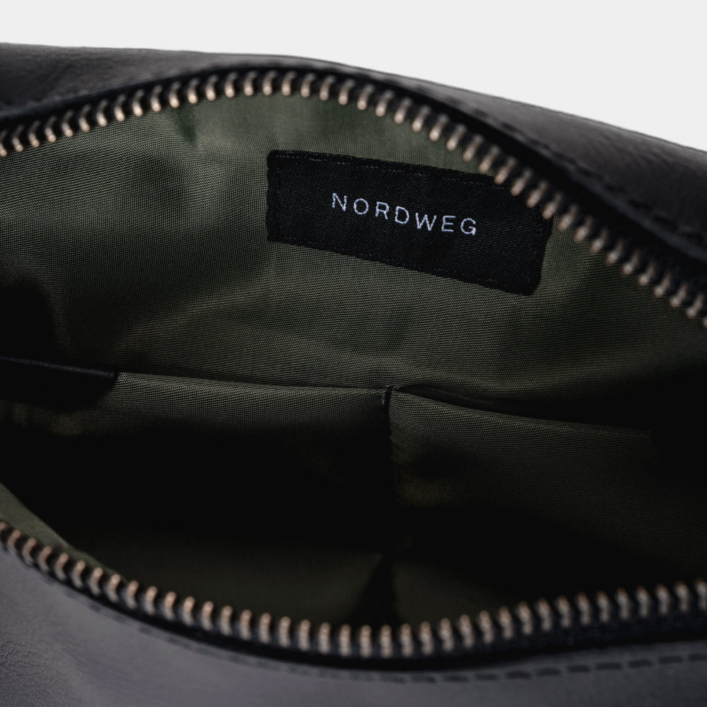 Open black Pulse leather sling bag showing organized interior and green lining