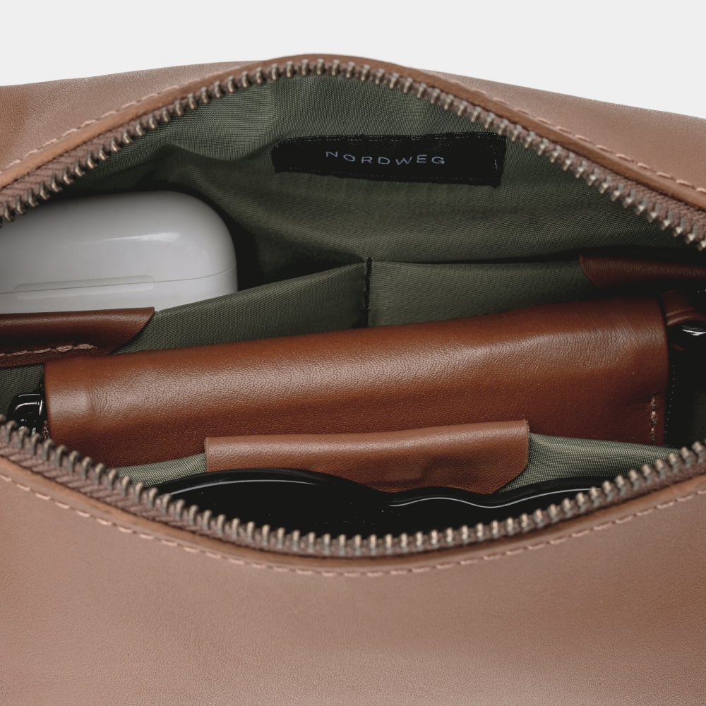 Open caramel Pulse leather sling bag showing organized interior and green lining