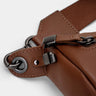 Close-up of caramel Pulse leather sling bag zipper lock and hardware detail