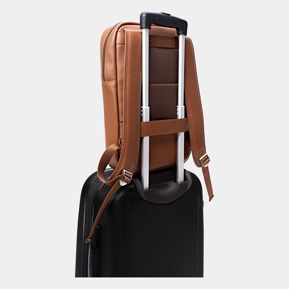 Caramel Slim Workplace backpack secured over a rolling suitcase handle