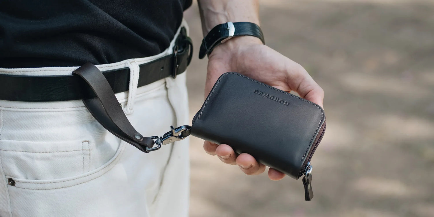 Nordweg Traveler Pro AirTag leather wallet in Black held with wrist strap safety loop, SKU NW111.IP, GTIN 7898571002171