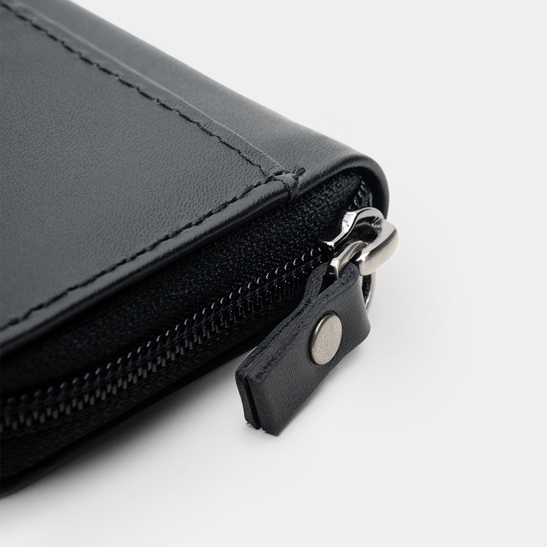 Close-up of black Traveler Pro AirTag leather wallet zipper pull and closure detail