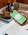 Caramel Nordweg Traveler Pro AirTag leather wallet beside a phone showing the Find My screen