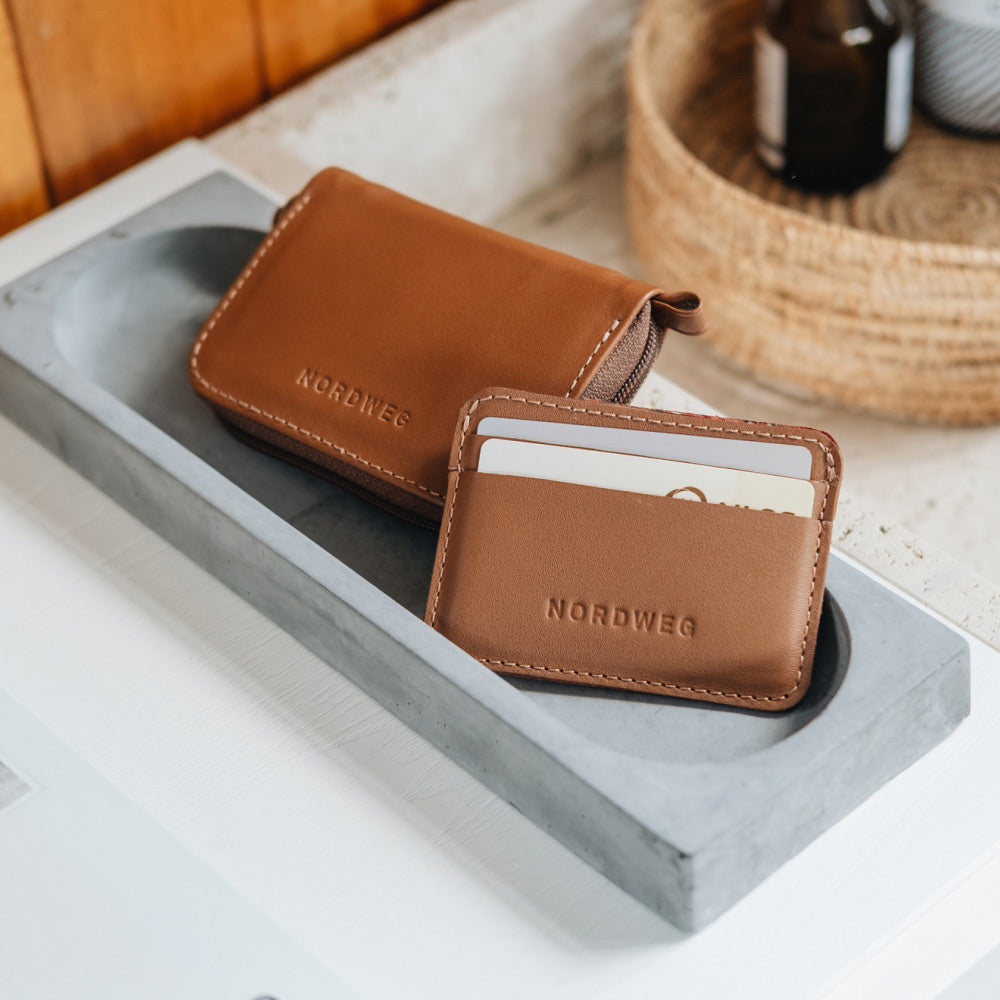 Caramel Traveler Pro AirTag wallet with matching mini cardholder on a tray