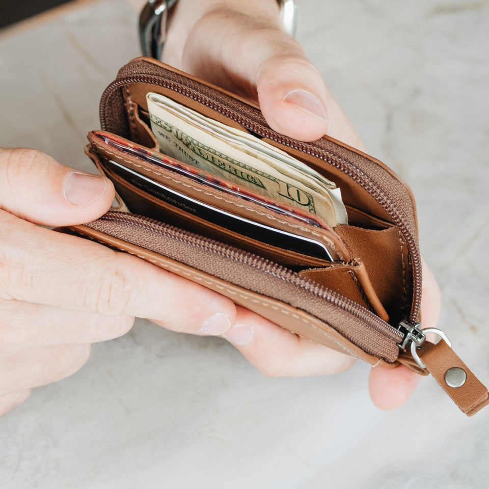 Nordweg Traveler Pro AirTag leather wallet in Caramel open with cash, cards, zip pocket, and wrist strap, SKU NW111.CA, GTIN 7898571002195