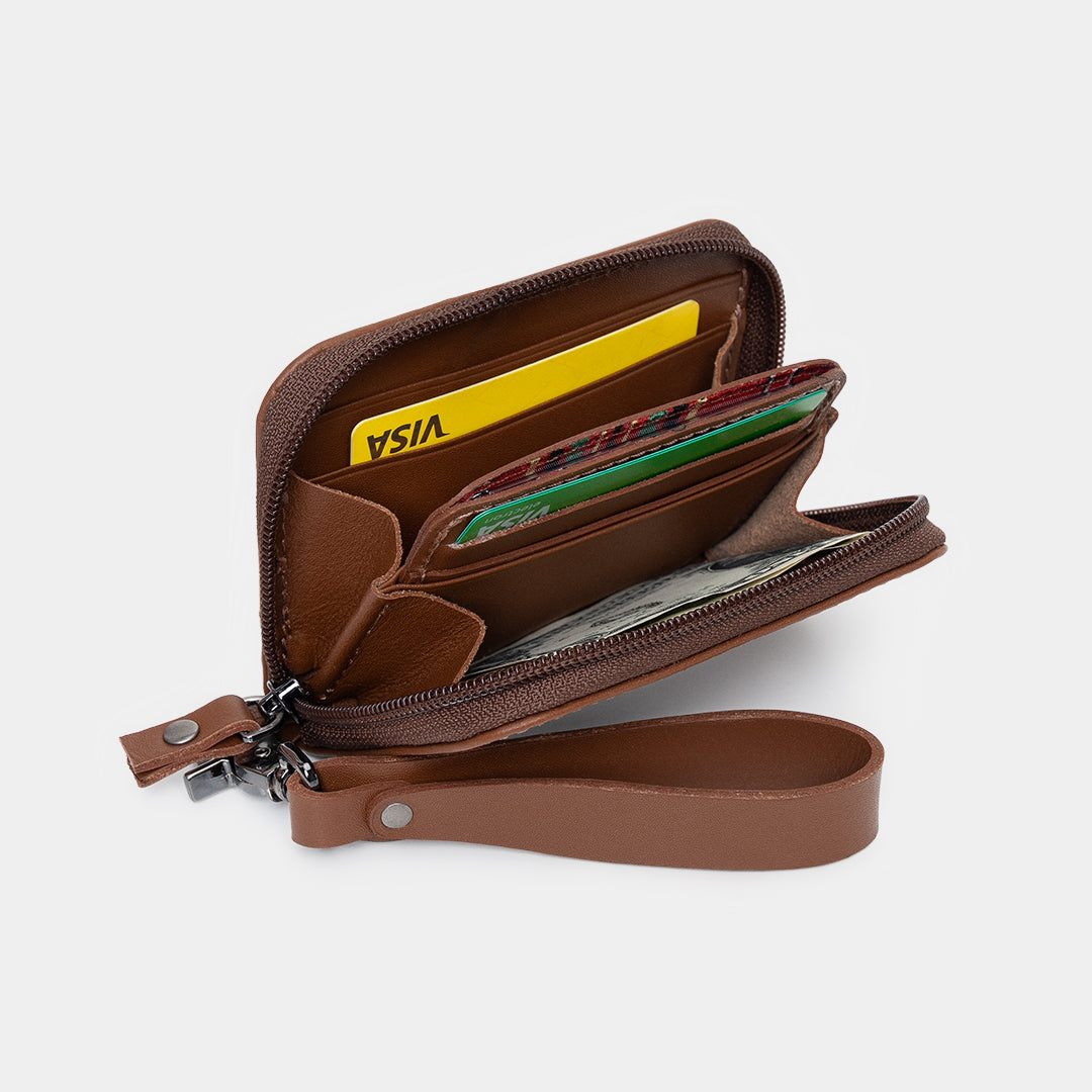 Open caramel Traveler Pro leather zip wallet showing card slots, cash pocket, and wrist strap