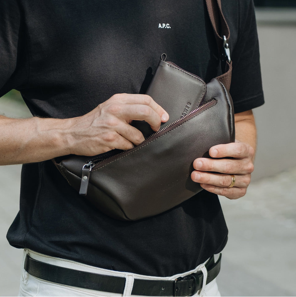 Coffee Nordweg Traveler Pro leather zip wallet shown beside a larger sling bag for size, SKU NW110.IC