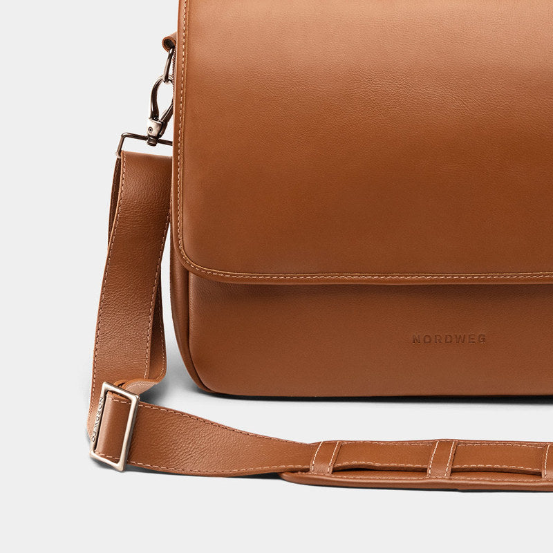 Close-up of caramel Workday leather briefcase front flap and shoulder strap